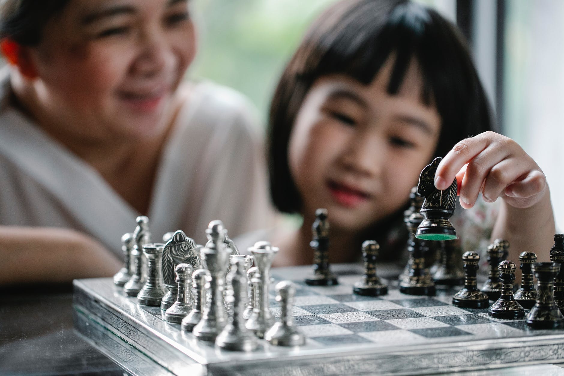 girl and grandmother playing chess